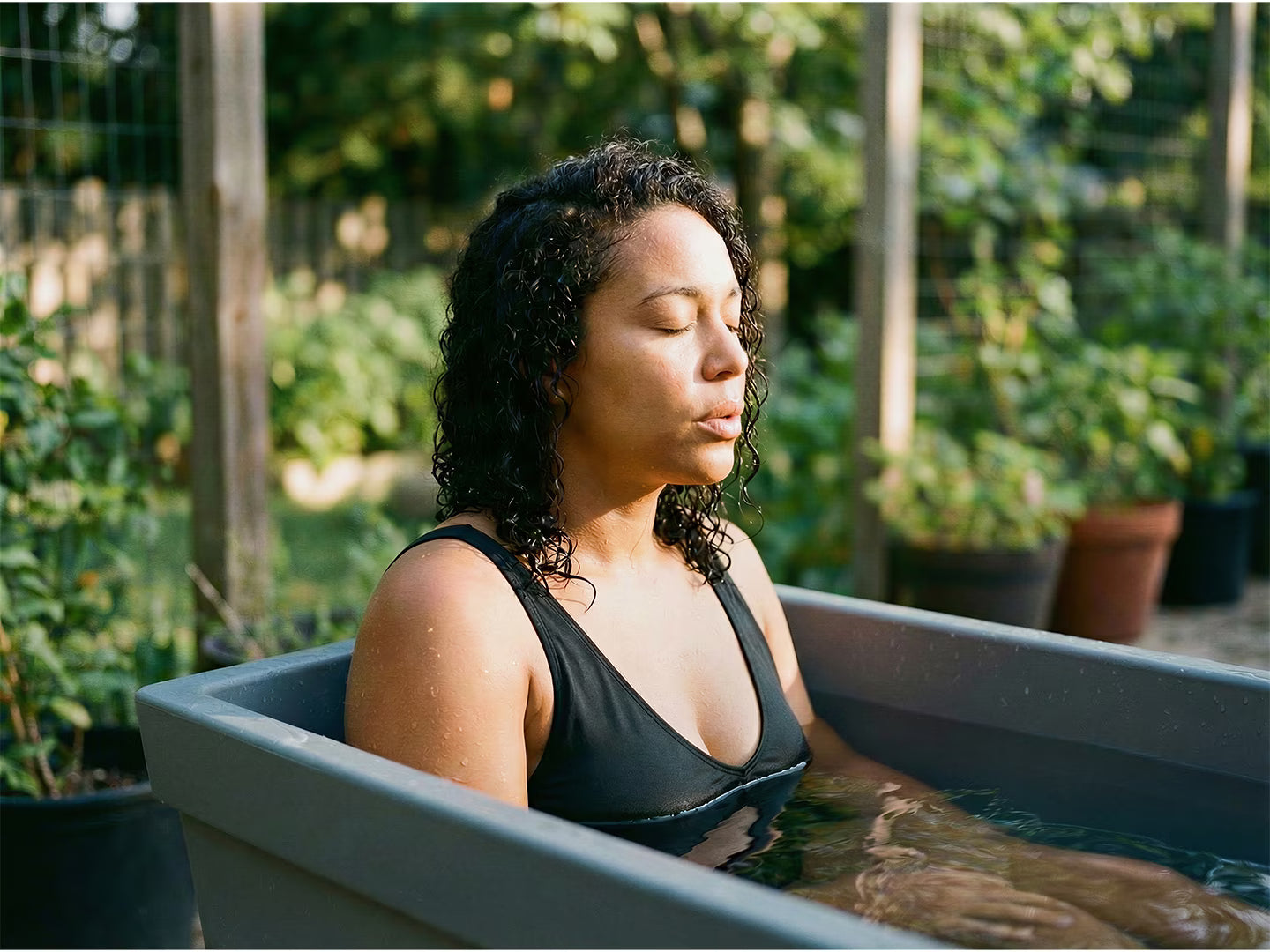 Woman relaxing in a bathtub outdoors with greenery around